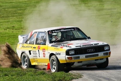 Audi-rallybil sladdar på grusväg med damm bakom sig